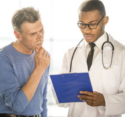 homem mais velho observa com atencao medico apresentado seu diagnostico em relatorio com capa azul