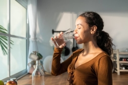 Mulher bebe água em sua casa