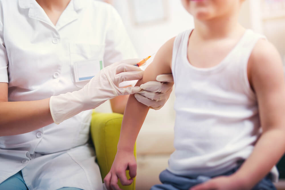 criança sendo vacinada no braço por uma médica