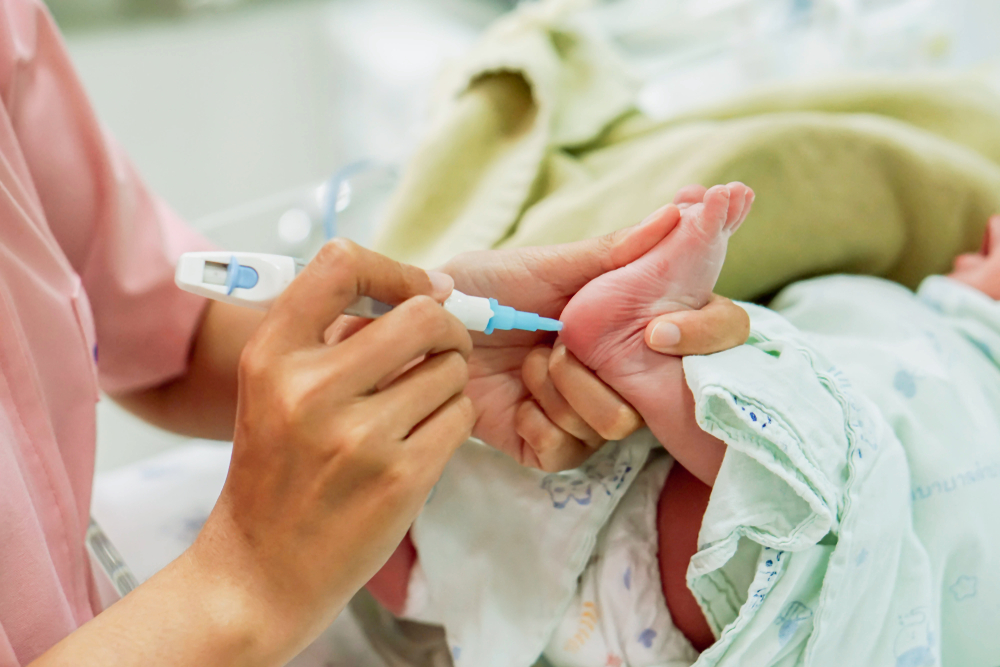 mãos de uma pediatra segurando o pezinho do bebê fazendo o teste do pezinho
