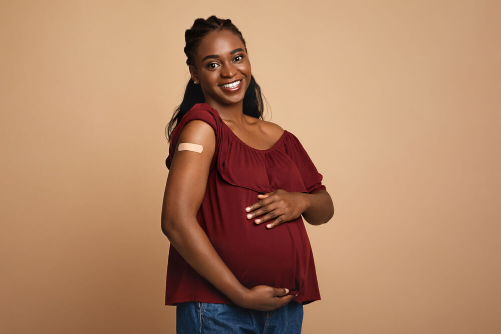 Mulher grávida mostra o braço após aplicar uma dose de vacinas para gestantes