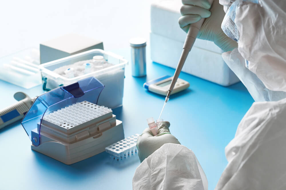Imagem de laboratório com uma profissional fazendo uma análise clínica de exame de PCR para Covid-19.