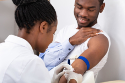Enfermeira segurando o braço do paciente para fazer o exame de sangue. A imagem ilustra o post sobre o que comer antes de fazer exame de sangue.