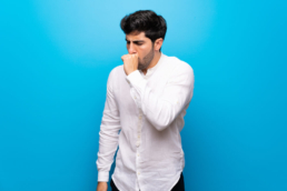 Homem com tosse seca, um dos sintomas mais comuns de Coqueluche