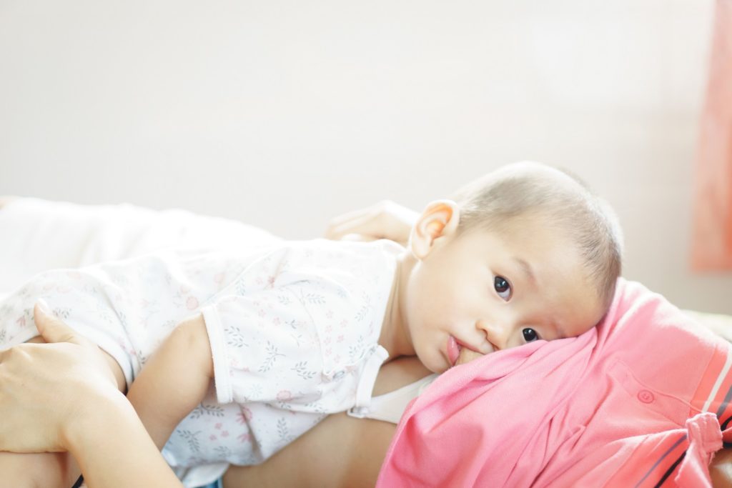 Uma imagem mostrando um bebê deitado no colo da mãe se amamentando de leite materno