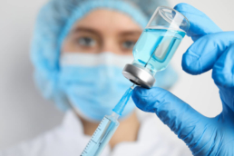 uma profissional de saúde segurando uma seringa e um recipiente com liquido da vacina - o que é vacina