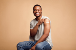 Homem afrodescendente mostra o braço com o curativo depois de ter se protegido contra uma das doenças preveníveis por vacinas