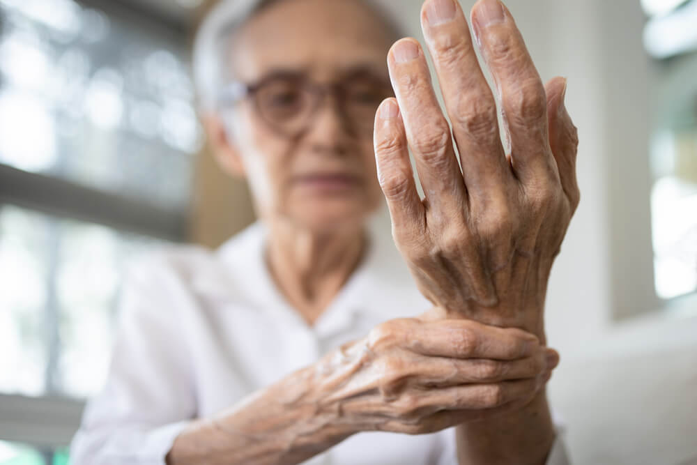 uma senhora está segurando o pulso com a outra mão dando sinais de artrite reumatoide na mão