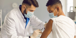 um médico aplicando uma vacina no braço de um menino - campanha de vacinação da gripe