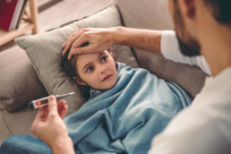 Pai mede a temperatura de uma criança gripada, que representa casos de gripe