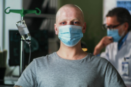Homem de máscara careca fazendo tratamento contra o câncer anal