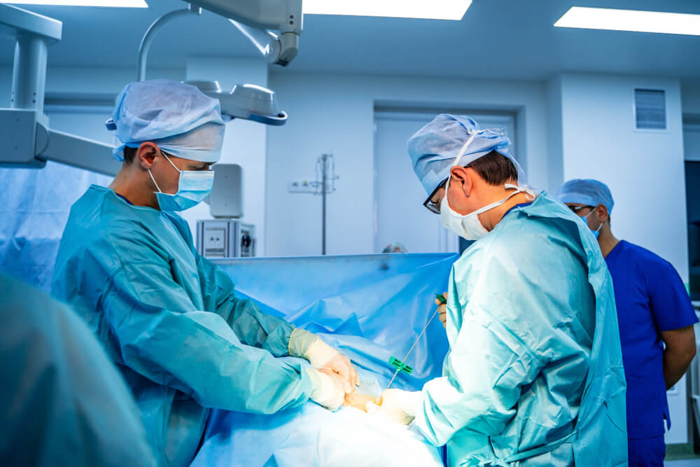 Sala de cirurgia com dois médicos fazendo uma coleta de medula óssea de um doador