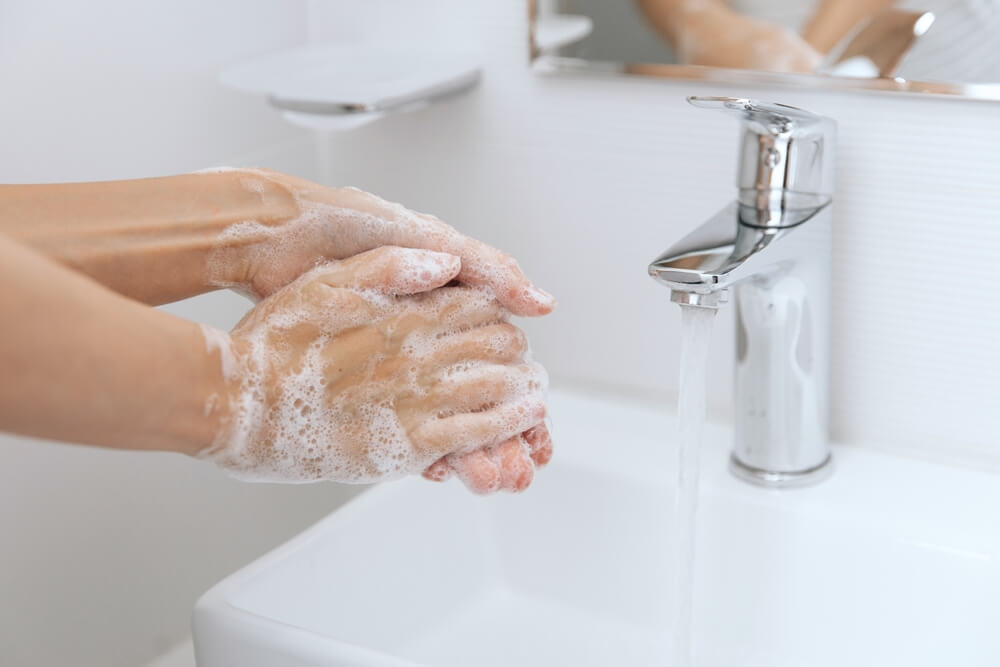Pessoa lavando as mãos na pia para evitar a amebíase