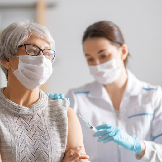 uma profissional da saúde aplicando o medicamento sybravaem uma idosa