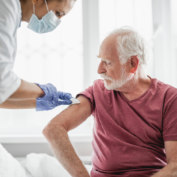Uma profissional de saúde aplicando a vacina contra gripe efluelda em um idoso